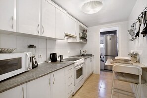 Una cocina moderna con armarios blancos, un microondas, estufa y pileta.