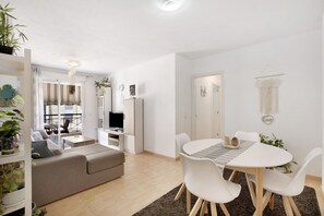 A modern living room with a sofa, dining table, chairs, and a TV.