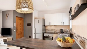 A modern kitchen with a dark countertop, white cabinets, a refrigerator, an oven, and a sink.