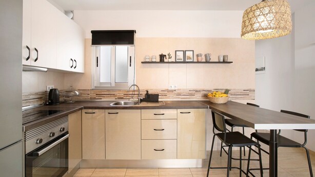 Una cocina moderna con una isla central, electrodomésticos de acero inoxidable y una lámpara colgante.