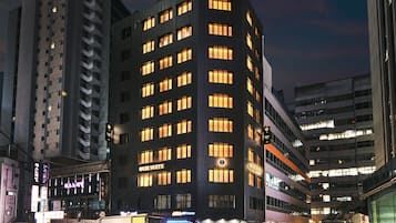 Un hôtel à plusieurs étages au design moderne, avec une enseigne bien visible indiquant « The Suite », de nombreux balcons et une façade bien éclairée.