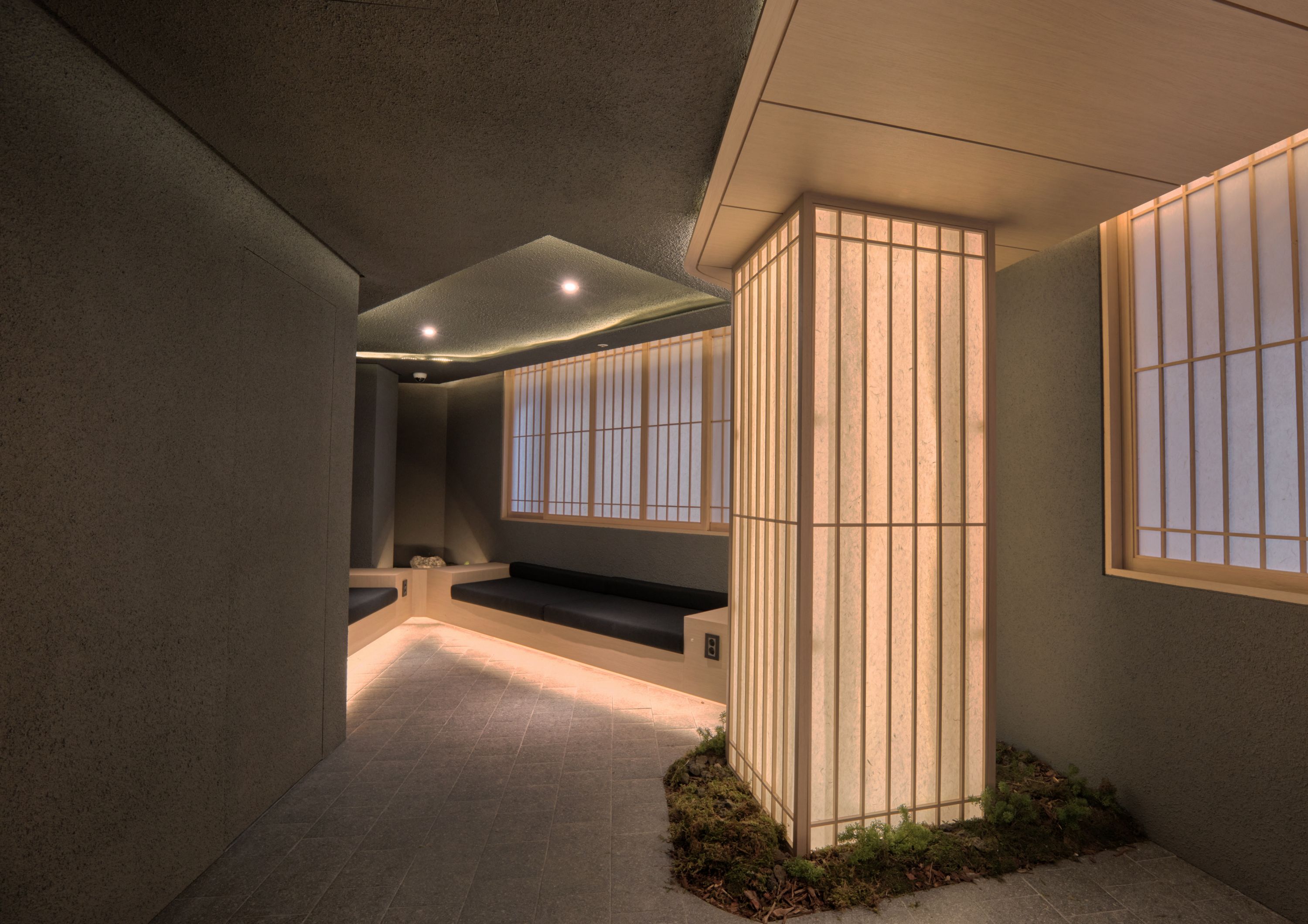 A corridor with a bench, a wall with vertical slats, and a window with bars.