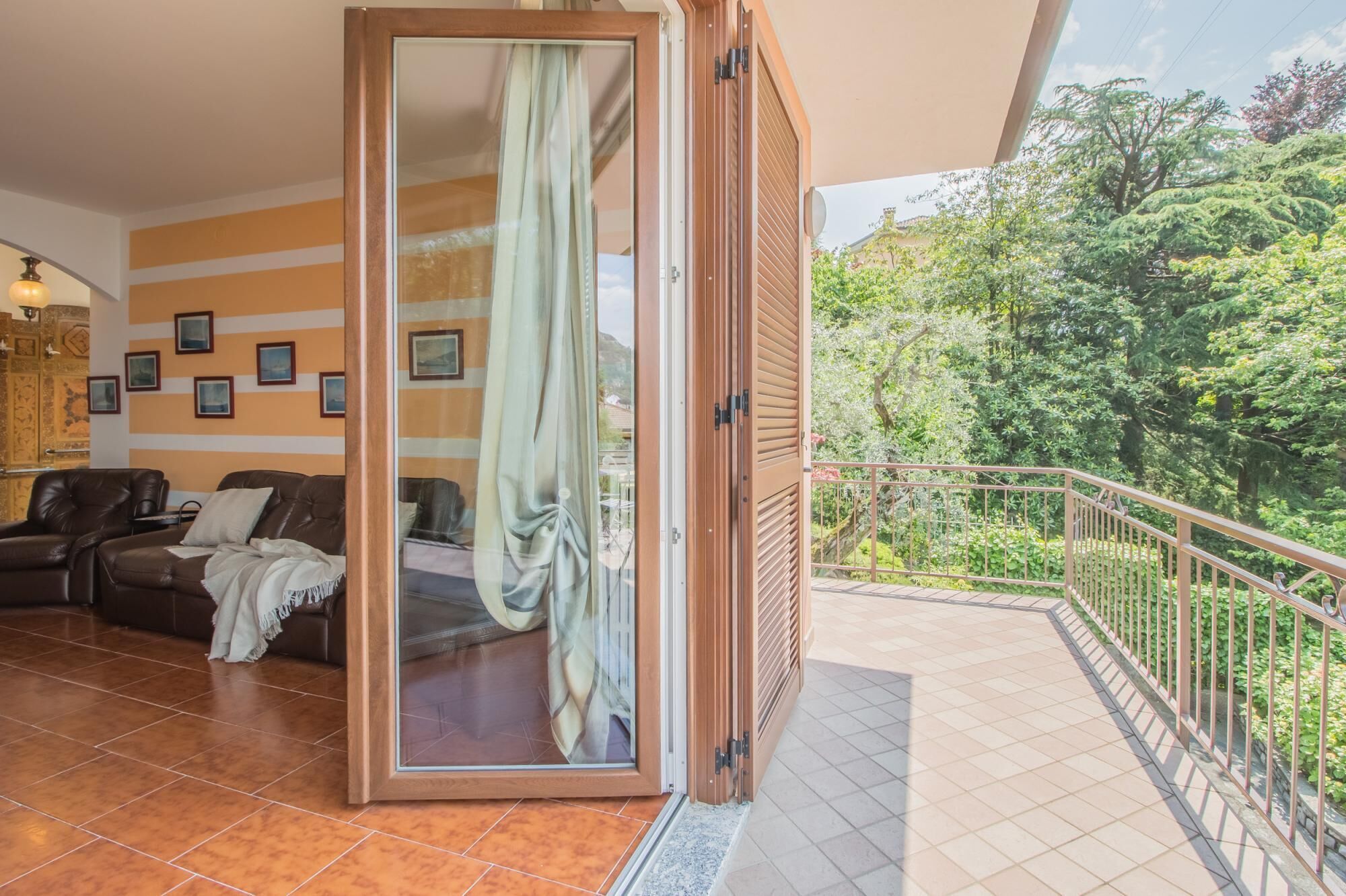 A room with a sliding glass door leading to a balcony with a metal railing.