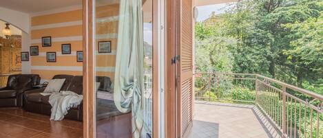 A room with a sliding glass door leading to a balcony with a metal railing.