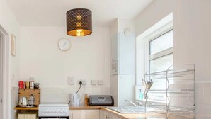 A compact kitchen with a gas stove, toaster, and a washing machine. - Stylish 4BD House With Private Garden - Stratford (London)
