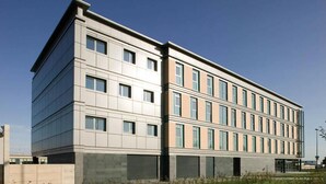 Un edificio moderno de varios pisos con tejado plano, ventanas grandes y fachada simétrica.