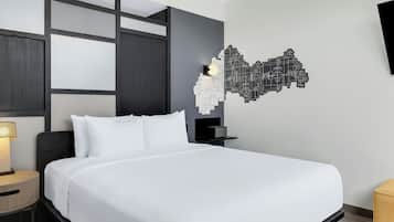 Habitación de hotel moderna con una cama grande, una mesita de noche con lámpara, un televisor montado en la pared y una decoración geométrica única en la pared.