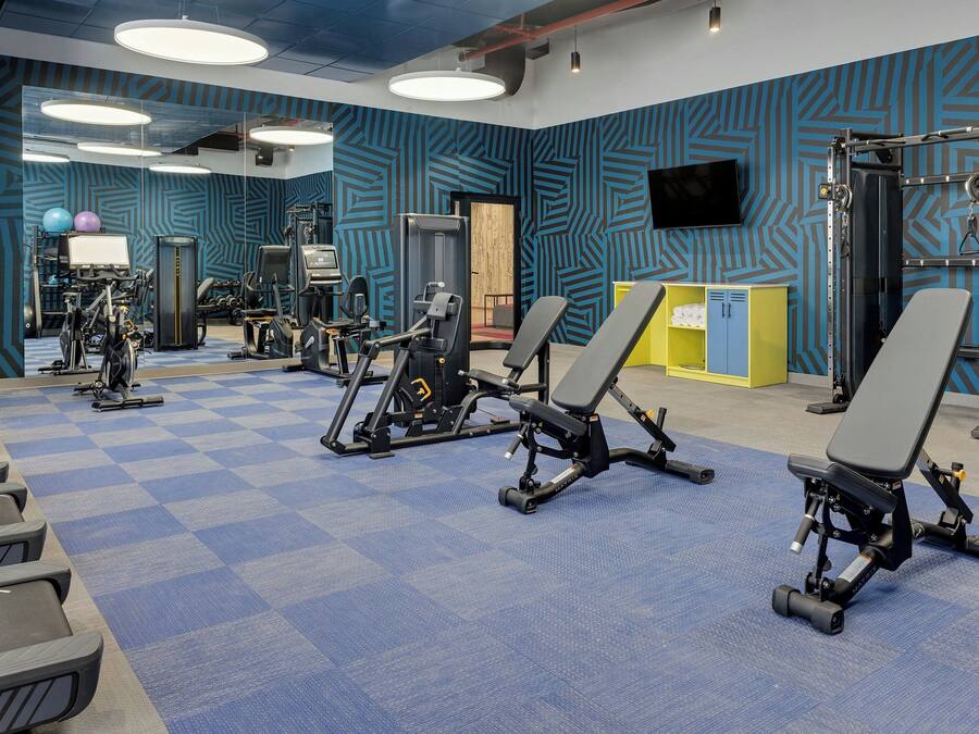 A gym with exercise equipment, a blue patterned wall, and a checkered floor.