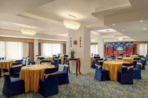 A conference room with round tables, chairs, and a stage with a banner.