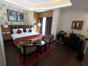 A hotel room with a bed, a desk, a chair, a TV, and a mirror.