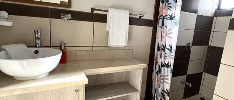Une salle de bain avec un lavabo blanc, un miroir et un rideau de douche.