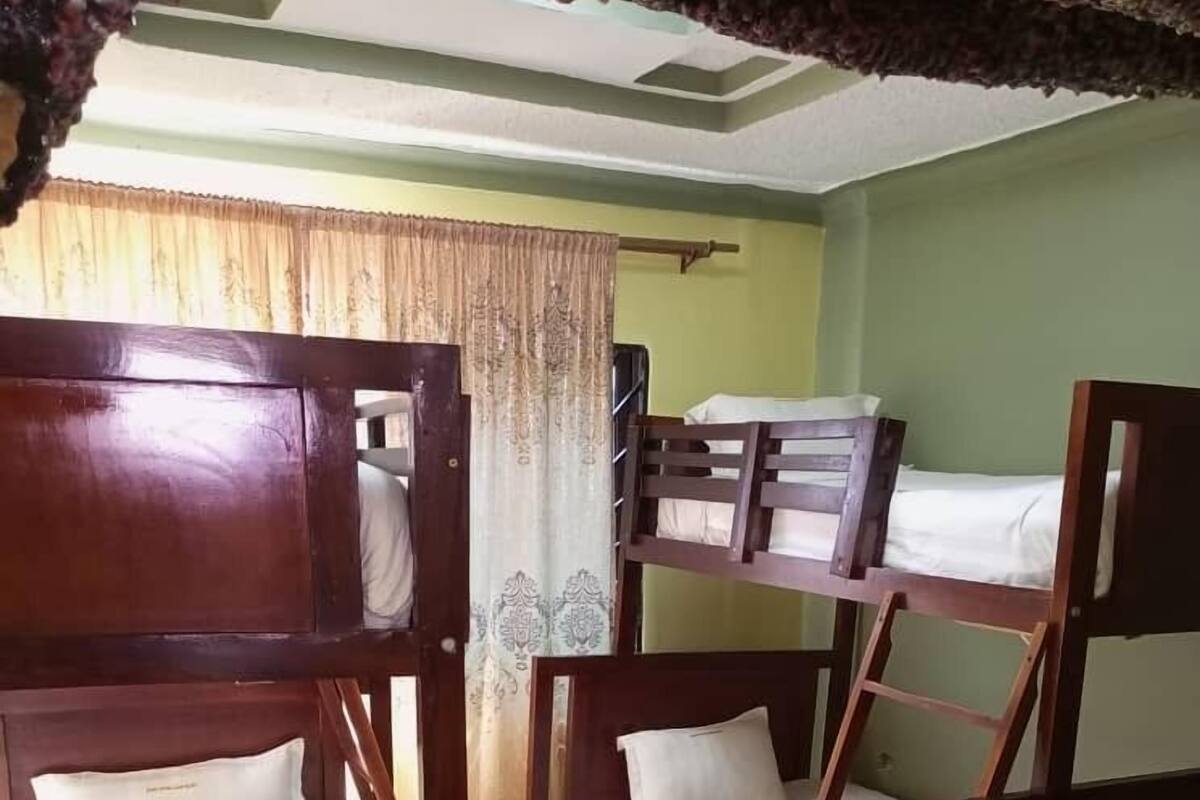 A room with bunk beds, a wooden floor, and a curtain.
