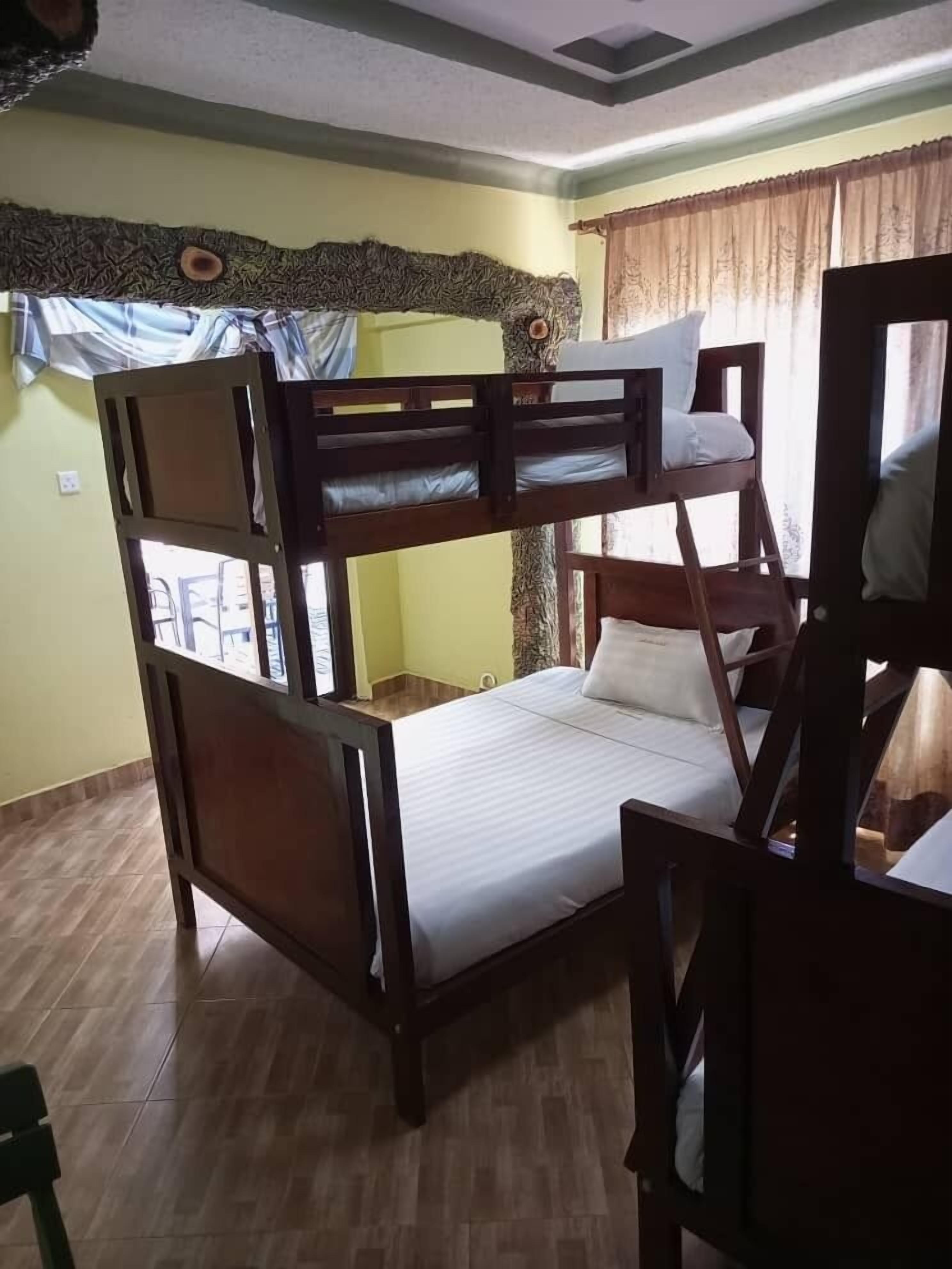 Habitación con literas de madera, una cama individual y una silla.