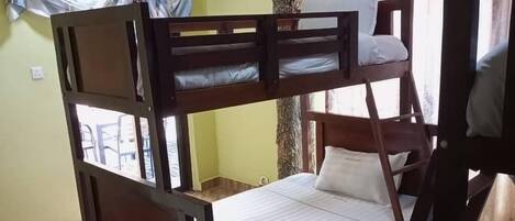 Habitación con literas de madera, una cama individual y una silla.