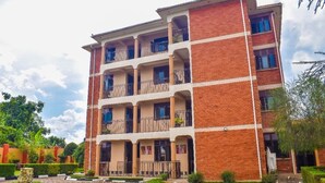 A multi-story hotel with a brick facade, balconies, and a courtyard with greenery. - The Spot Hotel (Mbale)