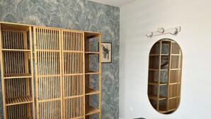 A room with a large wooden wardrobe, a round window, and patterned wallpaper. - Vue sur Mer, Appartement Rénové au Coeur de la Station Balnéaire (Agon-Coutainville)