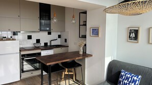 A modern kitchen with white cabinets, a wooden countertop, and black chairs. - Vue sur Mer, Appartement Rénové au Coeur de la Station Balnéaire (Agon-Coutainville)