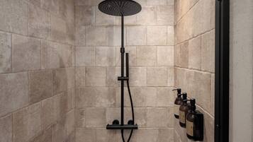 Eine Dusche mit Regendusche, Handbrause und Wandseifenspender.