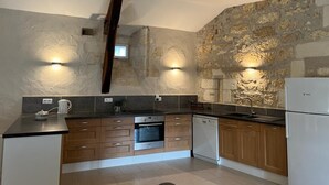 Una cocina con pared de piedra, armarios de madera y electrodomésticos modernos.
