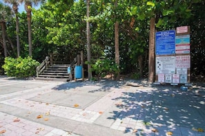 A park entrance with a wooden staircase, a trash bin, and multiple informational signs.