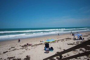 A beach with a clear sky, a sandy shore, and a few people and umbrellas.