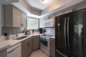A modern kitchen with stainless steel appliances, a dishwasher, and a microwave.