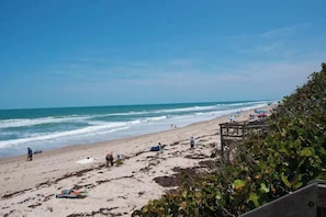 A beach with people, a wooden fence, and vegetation.