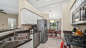 A modern kitchen with stainless steel appliances, white cabinetry, and a granite countertop. - `Saloma Place` Pet-Friendly! Large yard! Work Space! (Austin)