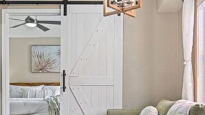 A cozy room with a sliding door leading to a bedroom, a green sofa, a round wooden table, and a fluffy white rug. - `Saloma Place` Pet-Friendly! Large yard! Work Space! (Austin)