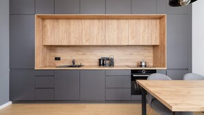 Una cocina moderna con armarios grises, encimera de madera y un comedor con mesa y sillas.