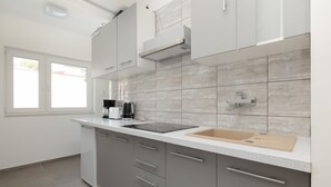 Una cocina moderna con armarios grises, encimera blanca, un lavabo y un ventanal.