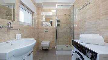Un bagno moderno con lavandino, water, doccia e lavatrice.