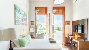 A bedroom with a bed, a desk, a TV, and a painting on the wall. - SPECTACULAR seaside Villa & POOL, Harbour & Ocean views, STARLinK, BBQ,6 bedroms (Santa Teresa Rio de Janeiro)