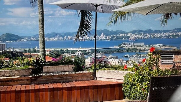 A pool with a view of a city and the sea, a bench, and umbrellas. - SPECTACULAR seaside Villa & POOL, Harbour & Ocean views, STARLinK, BBQ,6 bedroms (Santa Teresa Rio de Janeiro)