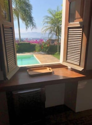 Une chambre avec une fenêtre donnant sur une piscine et un jardin.