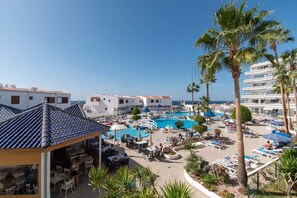 A resort with a swimming pool, outdoor seating, and palm trees. - Club Atlantis 120 - Studio with sea and pool view (Costa Adeje)