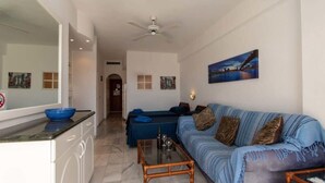 A living room with a sofa, coffee table, and a painting on the wall.