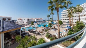 A resort with multiple swimming pools, palm trees, and a clear blue sky.