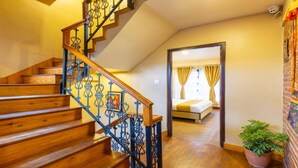 A staircase with wooden steps and blue metal railings leading to a bedroom with a bed and a potted plant. - MeroStay 190 HOMESTAY (Sainbu)