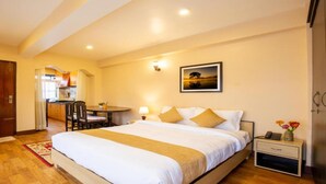 A hotel room with a bed, bedside table, and a view of the kitchen area. - MeroStay 190 HOMESTAY (Sainbu)