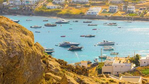 A coastal town with white buildings, a rocky shoreline, and numerous boats in the water. - Eden's Mykonos - Villa Opal (Mykonos)
