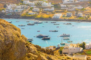 Experience the tranquil seaside atmosphere of this coastal town, where boats bob gently in the water and simple, functional architecture meets the rugged shoreline.