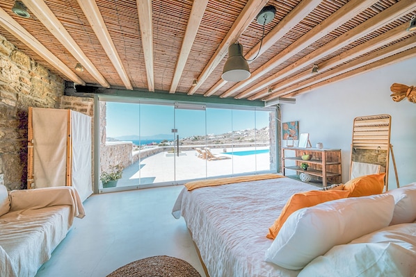 Relax in this serene bedroom with a large bed and stunning pool views from the balcony.