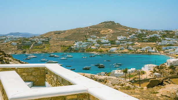 A coastal town with white buildings, a hilltop fortress, and boats in the water. - Eden's Mykonos - Villa Opal (Mykonos)