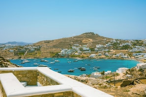 Stunning coastal town with white buildings and a historic hill in the background, surrounded by boats on the sea.