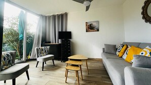 A living room with a grey sofa, a wooden coffee table, a TV on a black stand, and a ceiling fan. - Apartment for 4 in Argelès-sur-Mer with garden and garage (Argelès-sur-Mer)