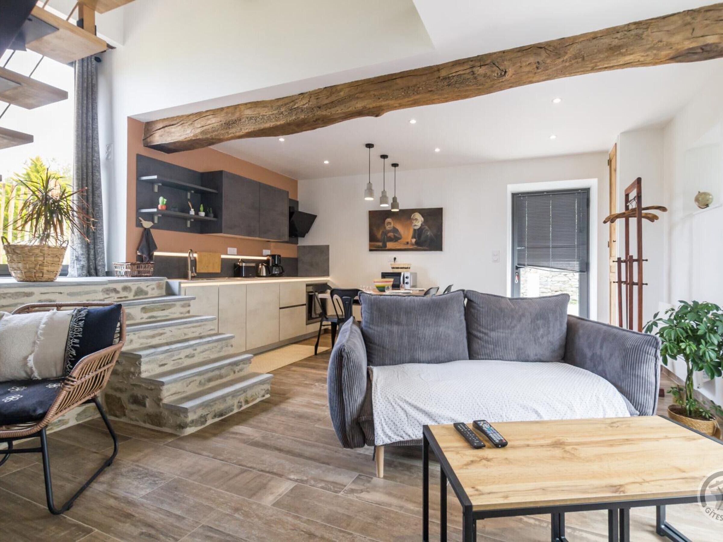 Un espace de vie moderne comprenant une cuisine, un coin repas et un coin salon confortable avec un canapé et une table basse.