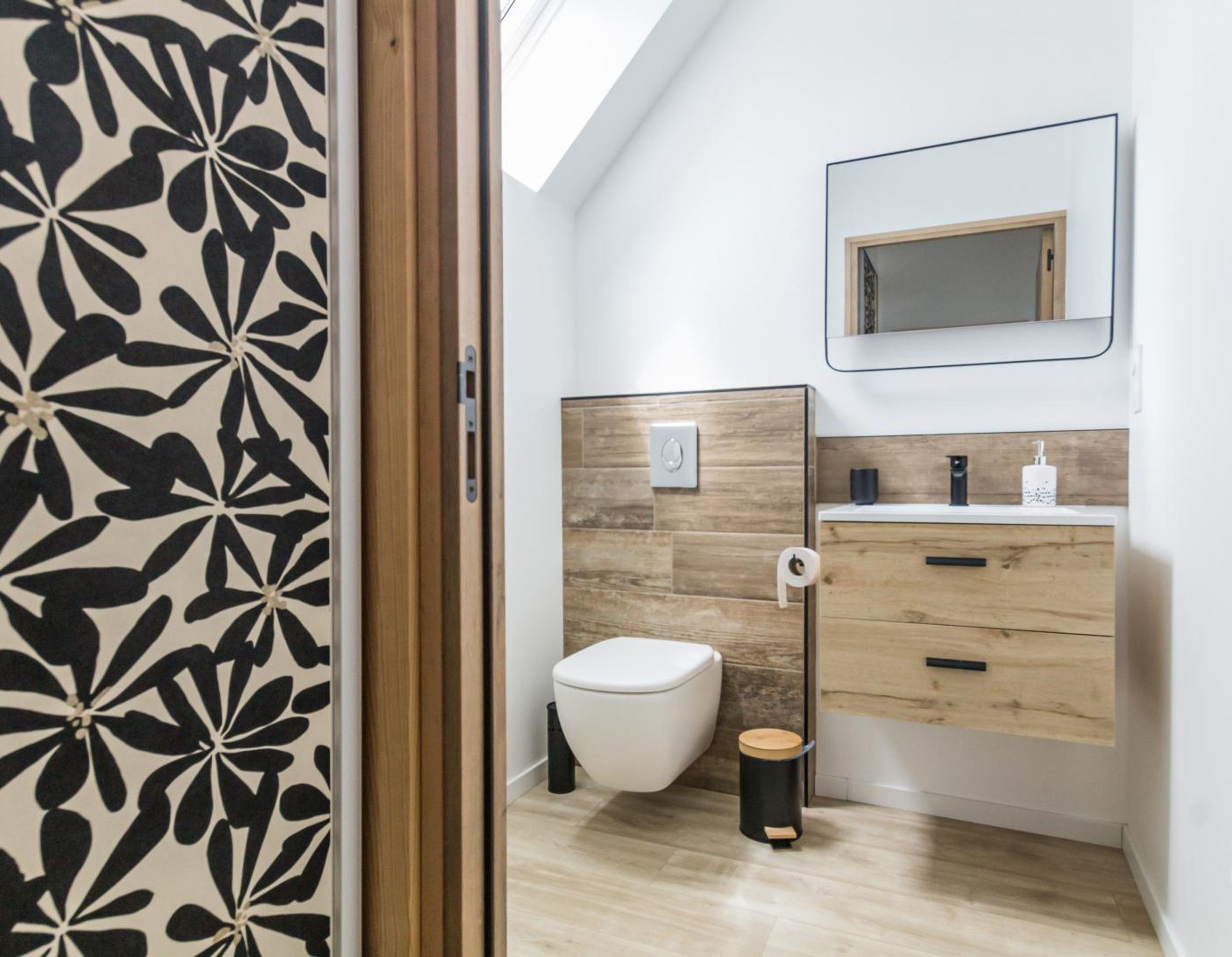 A modern bathroom with a toilet, a sink, and a mirror.