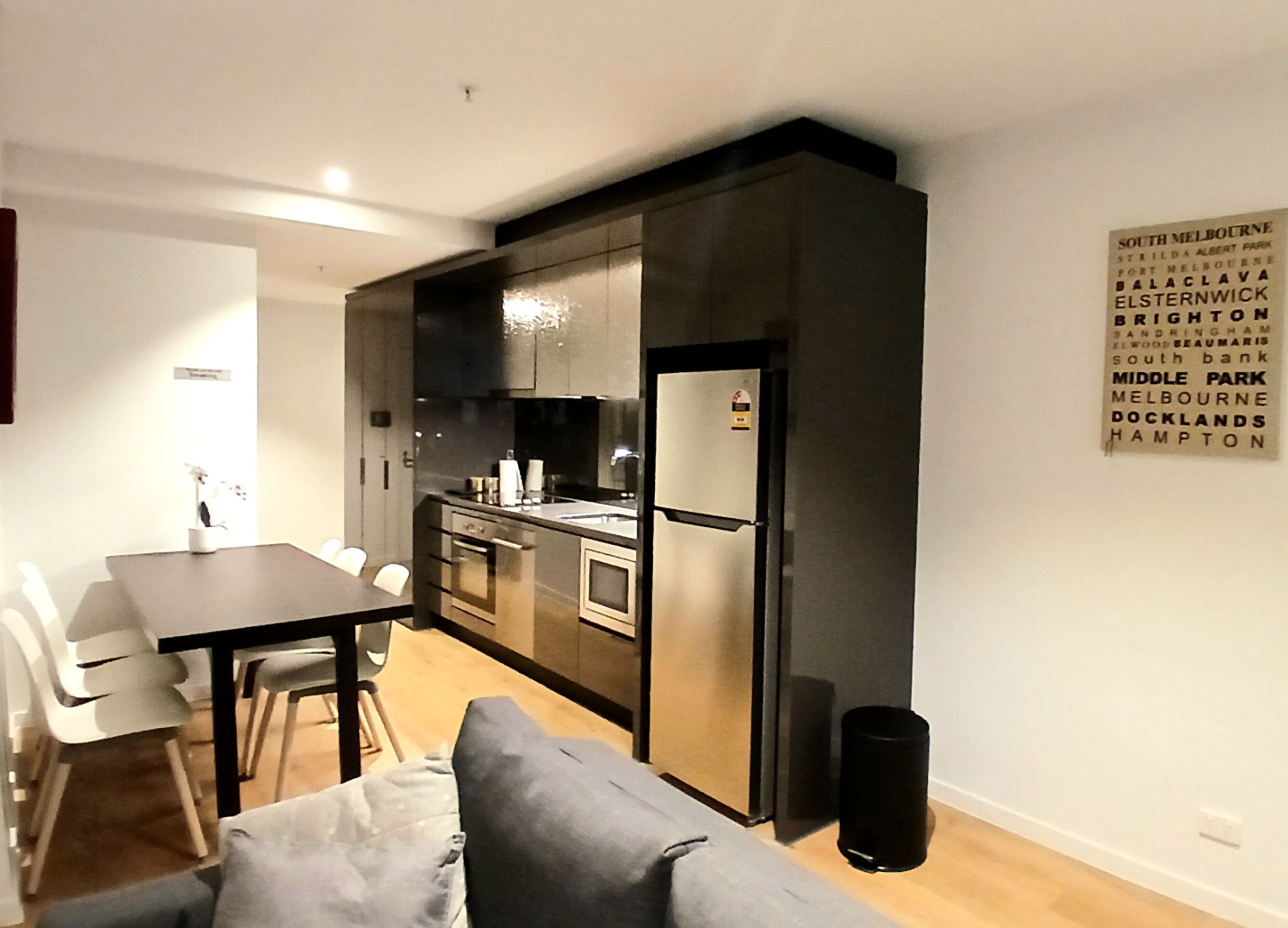 Una cocina compacta con electrodomésticos modernos, un comedor con mesa y sillas, y un sofá.