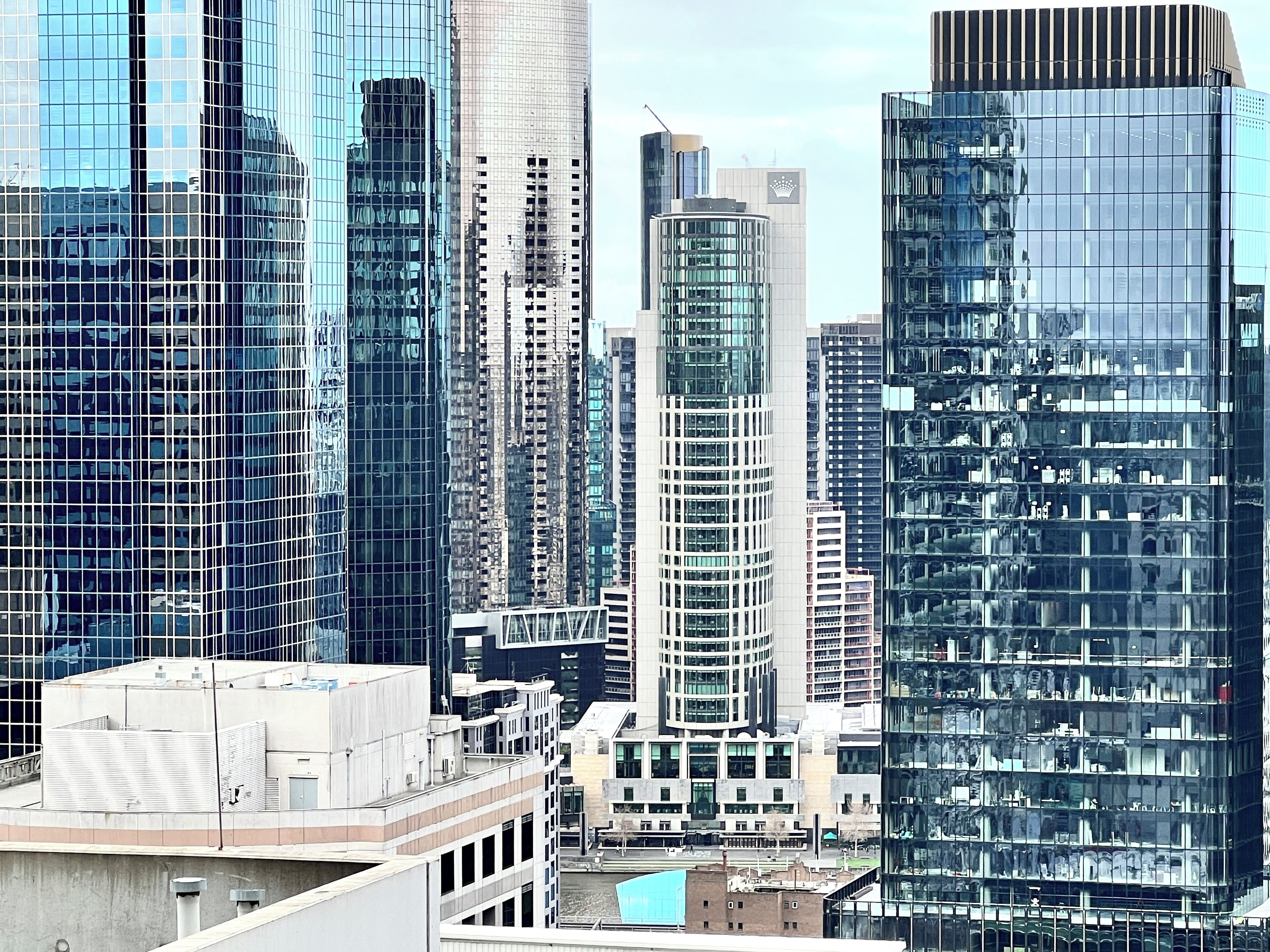 A cityscape with modern high-rise buildings, including a distinctive curved glass tower and a rectangular building with a flat roof.